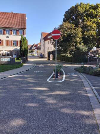 An einer Straße in der Innenstadt steht das Verkehrsschild Durchfahrt verboten. Die Straße ist mit Fahrrad-Piktogrammen markiert.