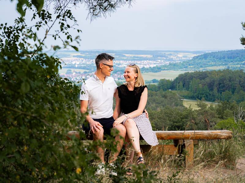 Eine Frau und ein Mann sitzen auf einer Bank in der Natur.