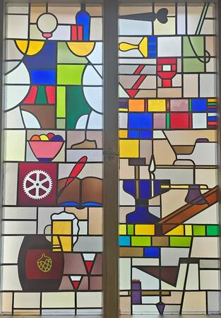 Ein Mosaikfenster im Rathaus mit verschiedenen historischen Gegenständen