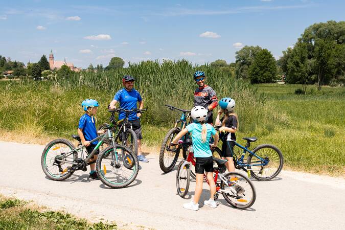Radfahrer treffen sich auf einem Radweg und unterhalten sich.