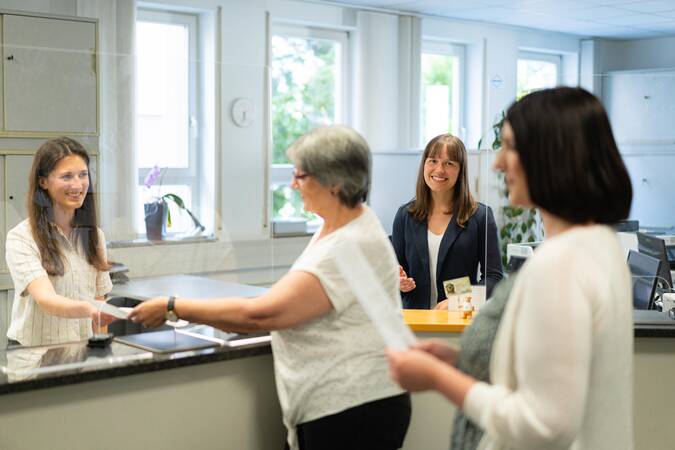 Zwei Bürgerinnen werden im Bürgeramt von zwei anderen Frauen beraten.