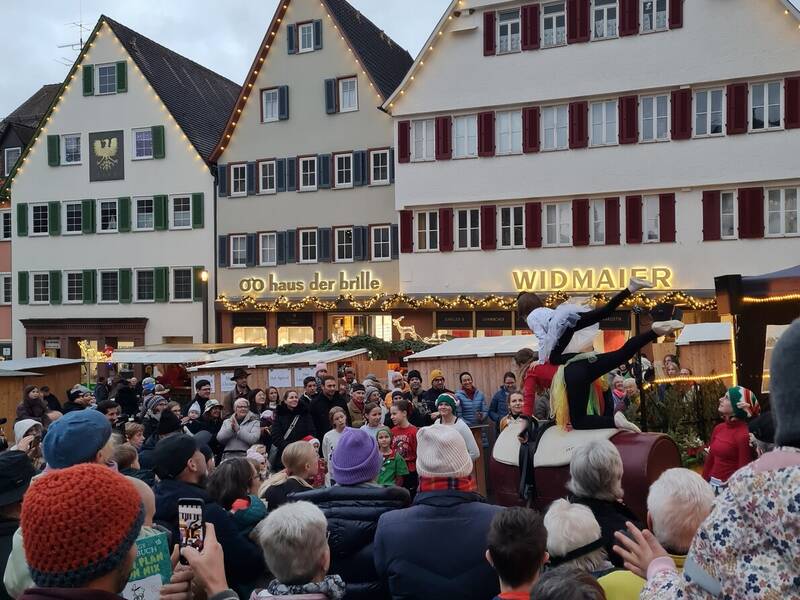 Eine Menschenmenge versammelt sich vor einem festlich dekorierten Gebäude, um einer akrobatischen Vorführung zuzusehen.