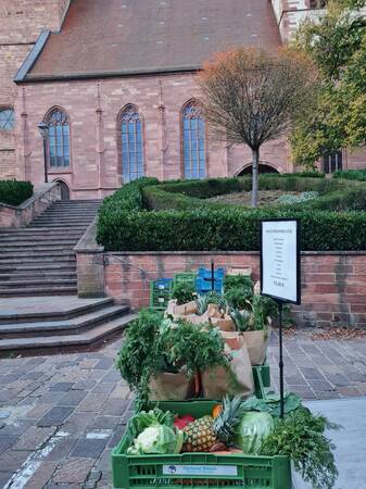 Tische mit gepackten Gemüsetüten und einer Kirche im Hintergrund