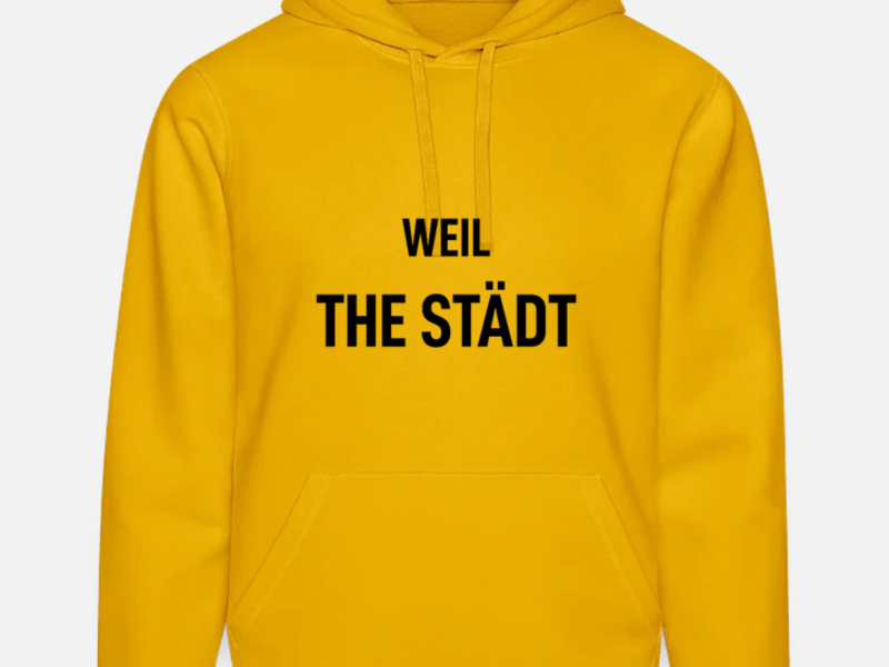 Ein gelber Hoodie mit der schwarzen Aufschrift "WEIL THE STÄDT" auf der Vorderseite.