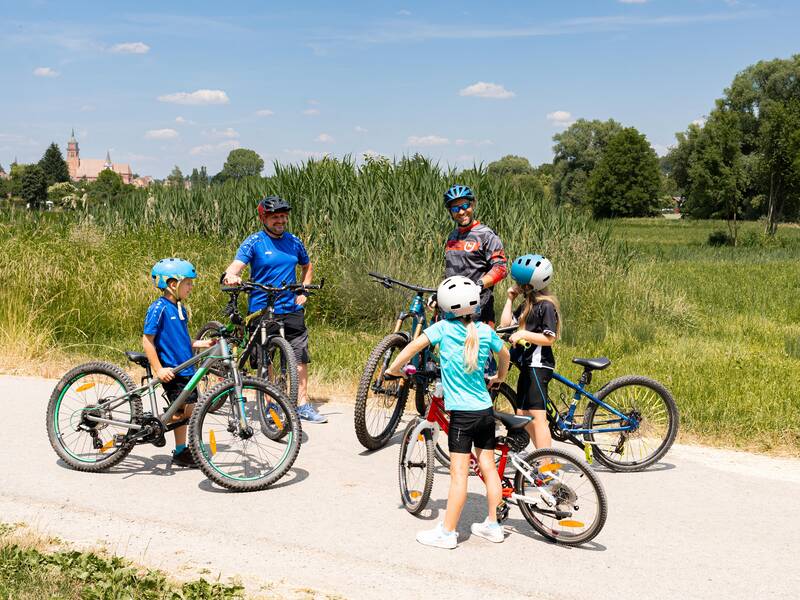 Radfahrer treffen sich auf einem Radweg und unterhalten sich.