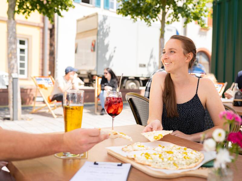 Eine Frau genießt das gastronomische Angebot auf dem Marktplatz der Stadt.