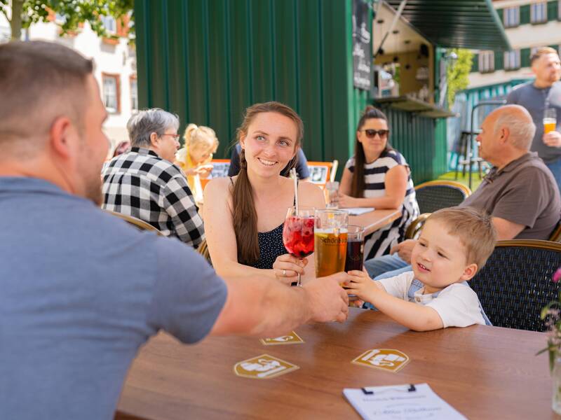 Eine Familie genießt das gastronomische Angebot auf dem Marktplatz der Stadt.
