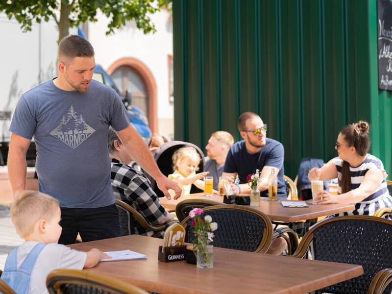 Eine Familie genießt das gastronomische Angebot auf dem Marktplatz der Stadt.