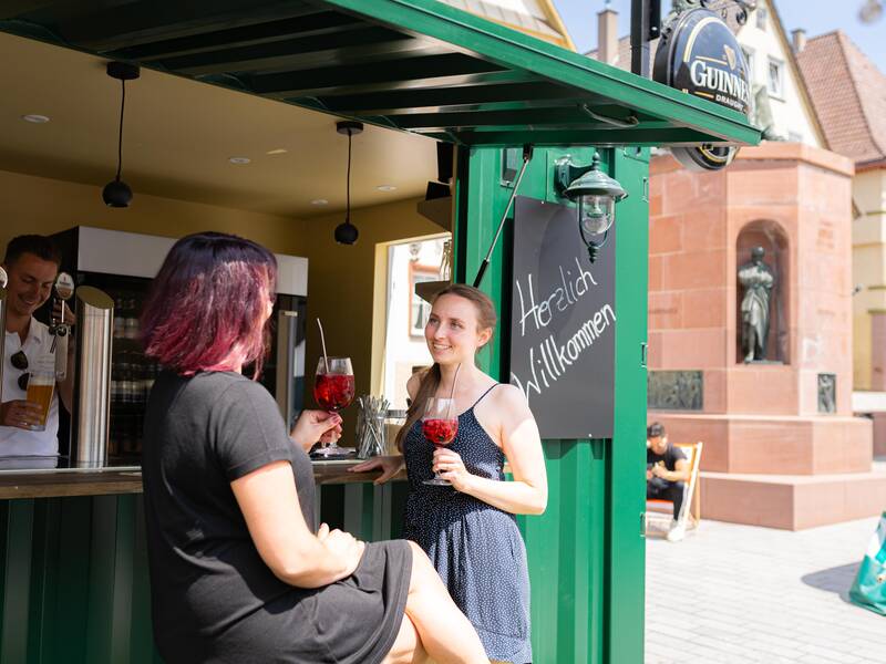 Zwei Personen genießen das gastronomische Angebot auf dem Marktplatz der Stadt.