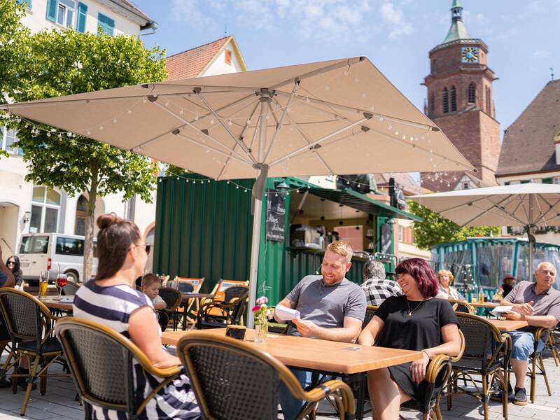 Eine Familie genießt das gastronomische Angebot auf dem Marktplatz der Stadt.