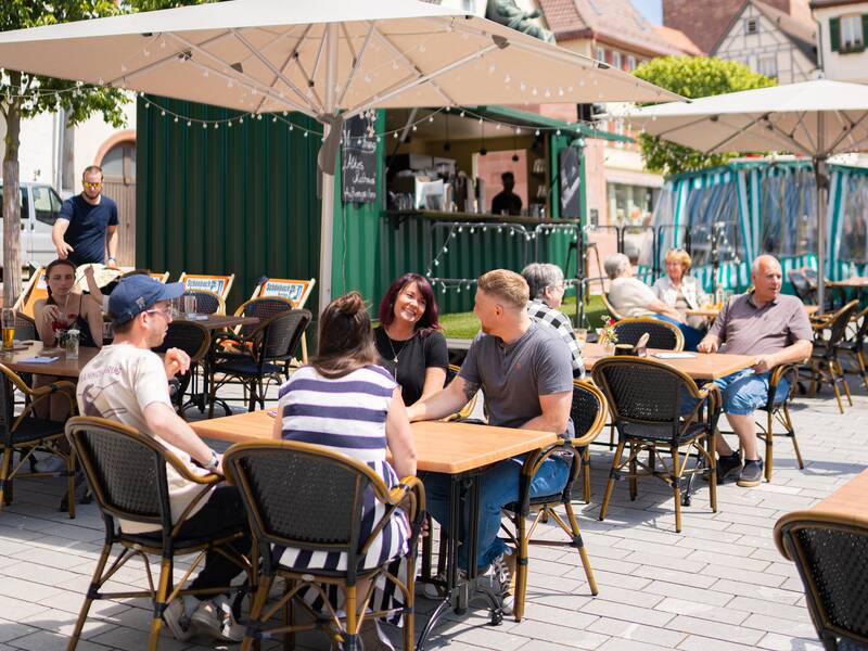 Eine Familie genießt das gastronomische Angebot auf dem Marktplatz der Stadt.