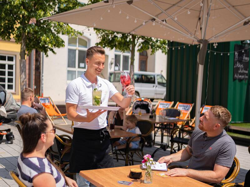 Eine Familie genießt das gastronomische Angebot auf dem Marktplatz der Stadt.
