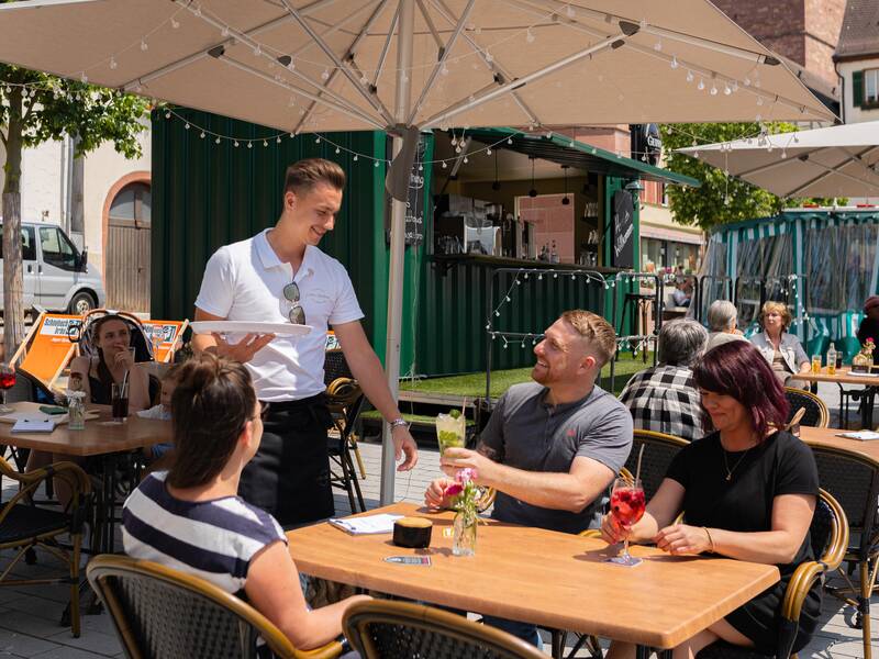 Eine Familie genießt das gastronomische Angebot auf dem Marktplatz der Stadt.