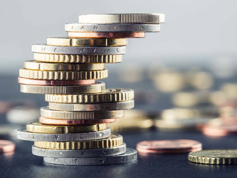 Im Vordergrund ist ein Stapel an Euro-Münzen. Im Hintergrund sind verschiedene Euro-Münzen verstreut.