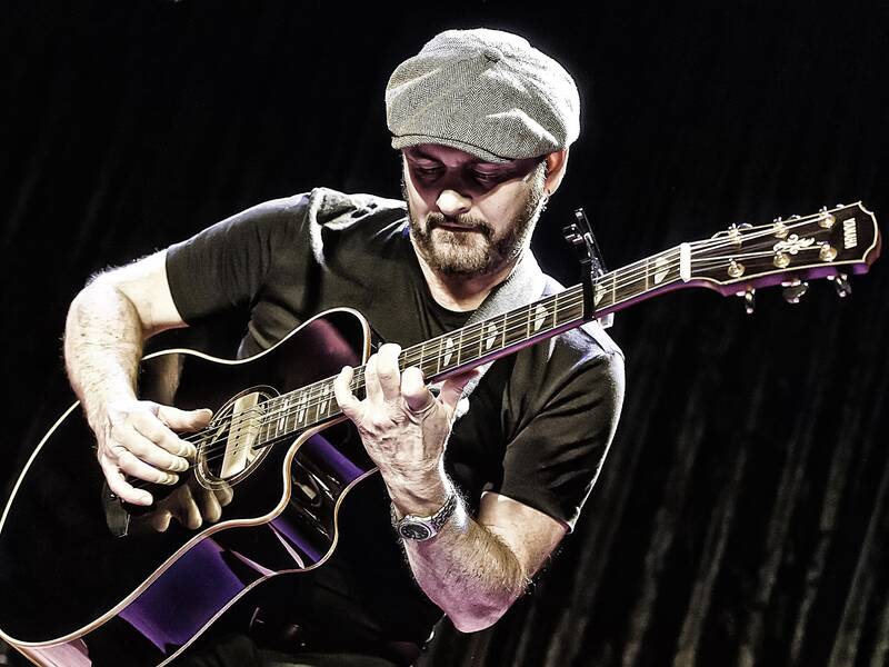 Ein Bild zeigt Dave Goodman, wie er seine Gitarre spielt.