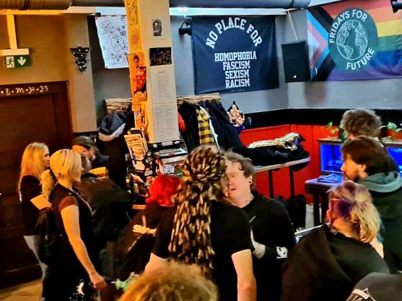 Viele Menschen stehen dicht beieinander in einer Bar und unterhalten sich.