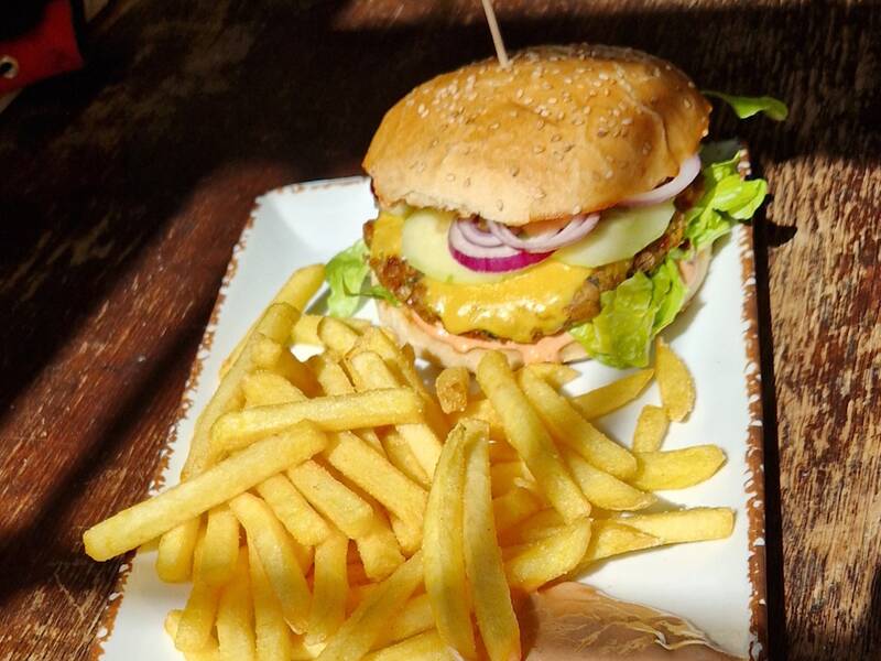 Auf einem Teller sind ein Cheeseburger mit Pommes.
