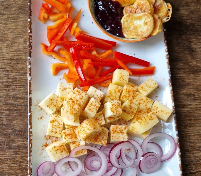 Einen leckeren Käseteller mit Zwiebeln, Paprika und Keksen. 